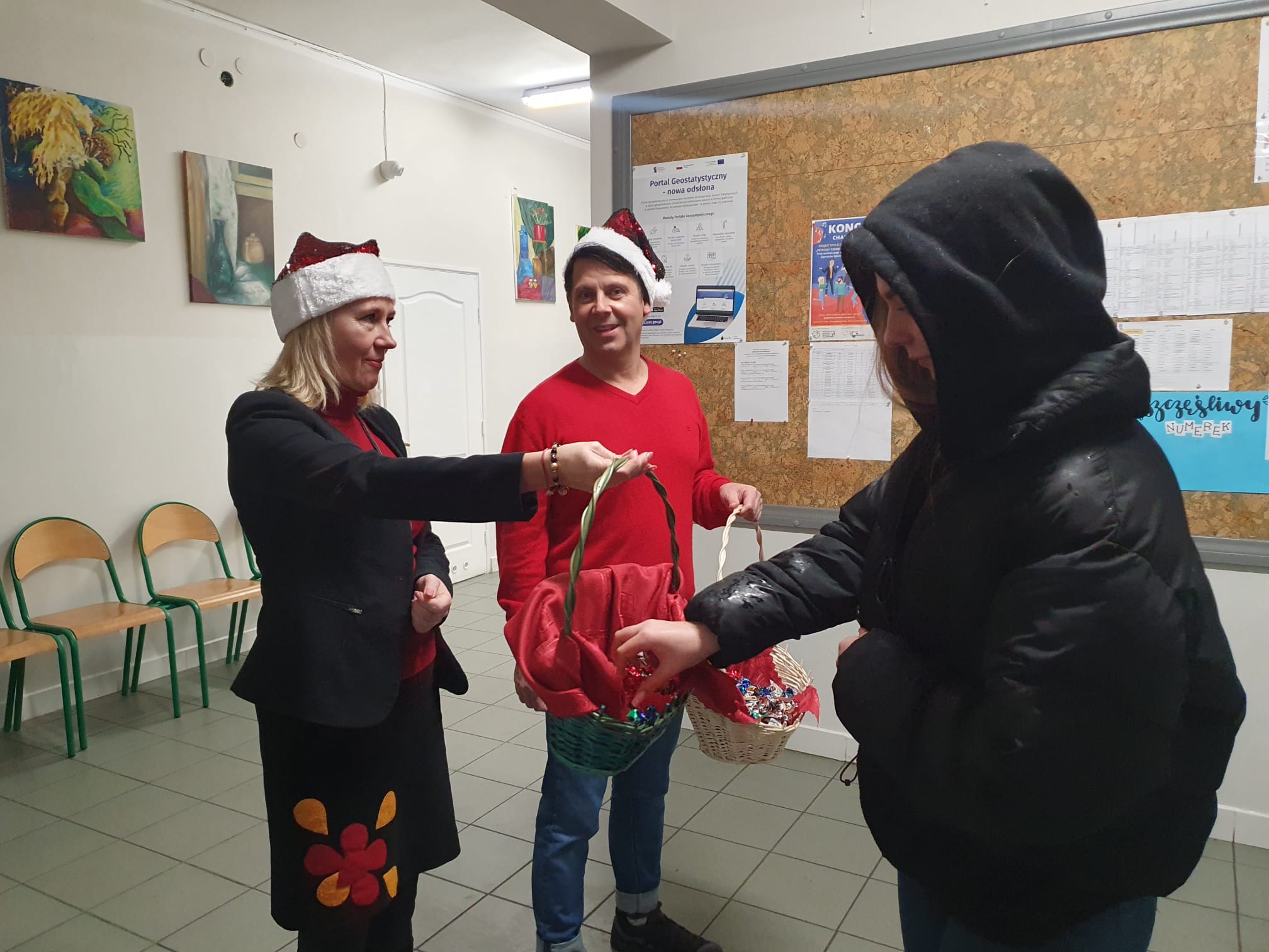 Dyrektor i Wicedyrektorka w strojach Mikołajów częstują uczniów