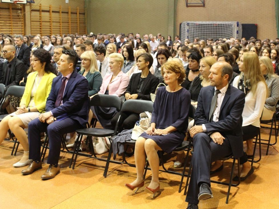 Siedzący na krzesłach uczestnilcy uroczystości początku roku szkolnego 2017/18. W pierwszym rzędzie dyrektor PIotr Niemiec, obok wicedyrektor Ewa Bońdos.