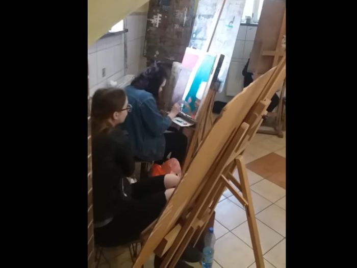 Dwie uczennice siedzą przy sztalugach i rysują