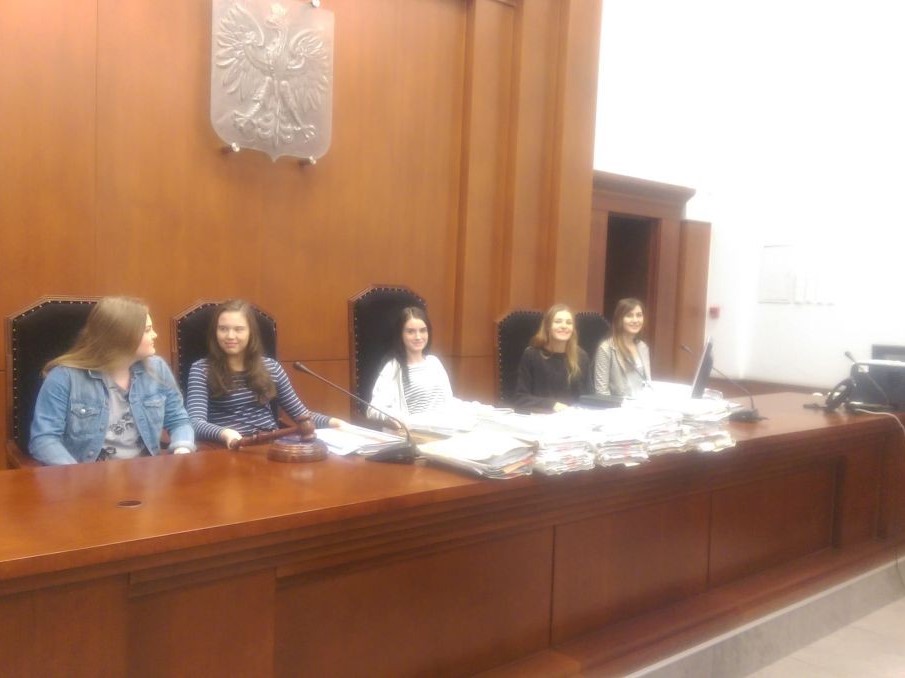 pięć młodych dziwecząt siedzi na miejscu sądu, na sali sportowej. 