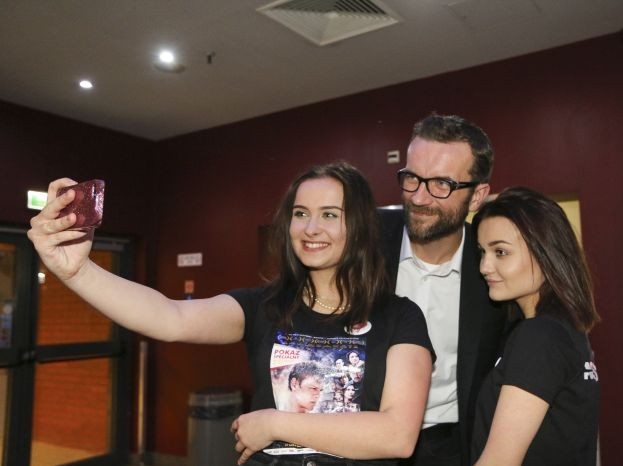 Widać trzy osoby. Pomiędzy dwoma młodymi dziewczynami stoi aktor Tomasz Kot. Wspólnie pozują do selfi, które robi dziewczyna po lewej stronie.