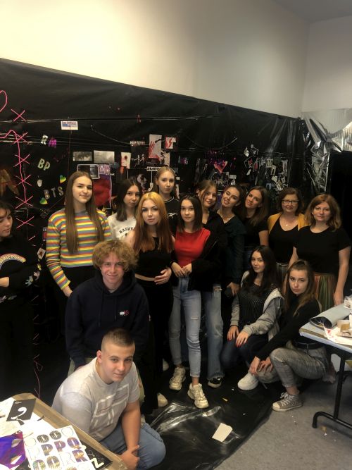 Grupa uczniów na tle ściany pokrytej wycinkamiz gazet