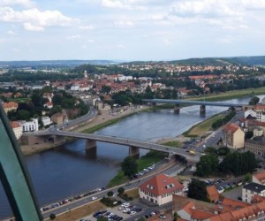 Widok na rzekę. Widać dwa mosty, łączą brzegi zapełnione budynkami.