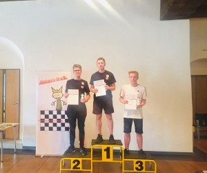 Trójka młodych mężczyzn stoi na podium prezentując dyplomy